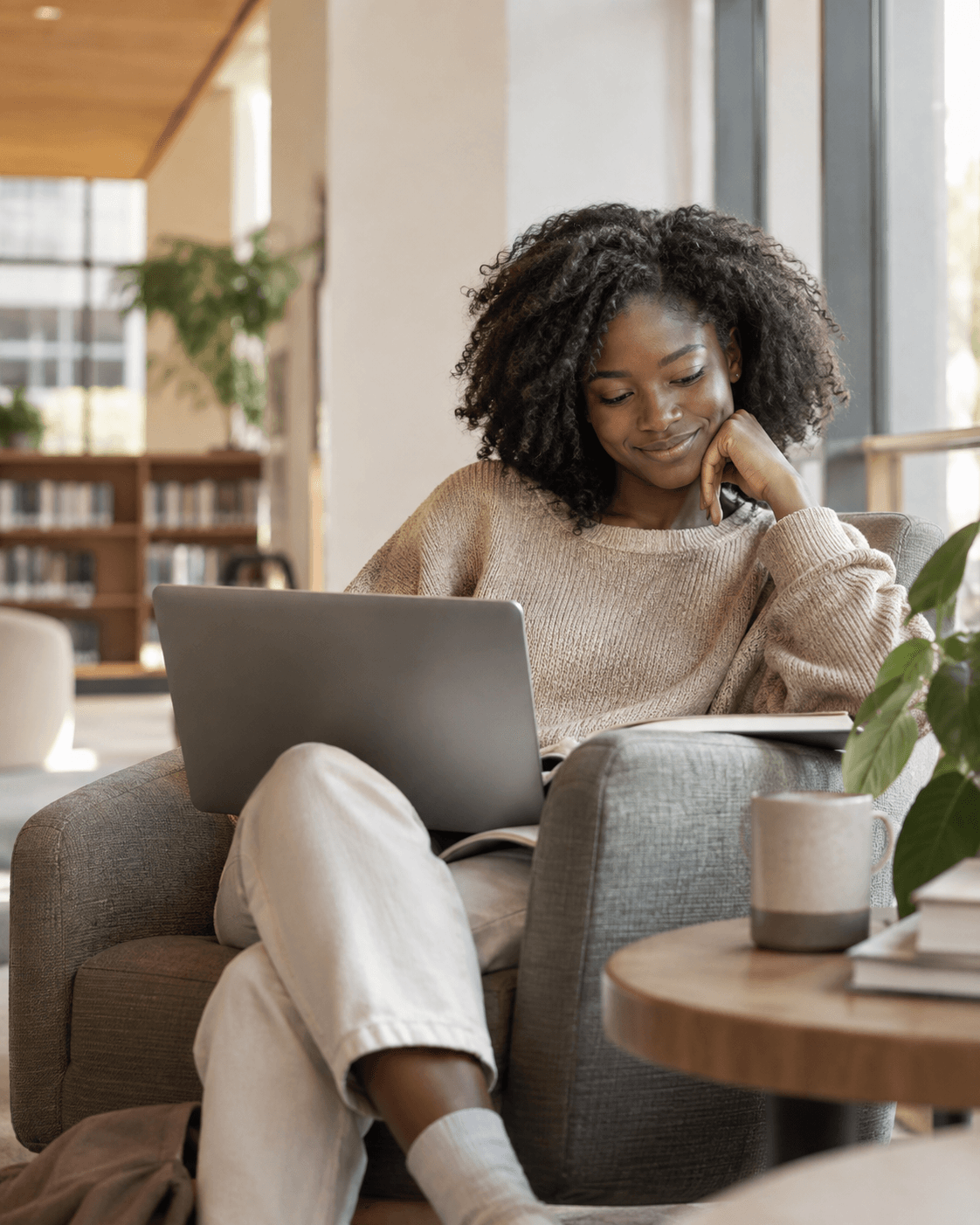 Student learning on a laptop in a bright library lounge